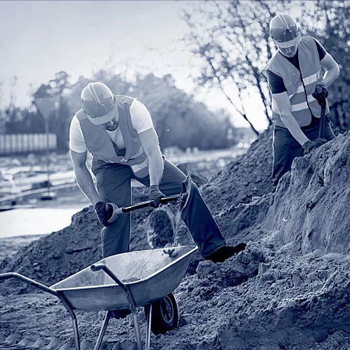 Zwei Bauhelfer beim Arbeiten auf einer Baustelle.