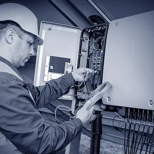 Ein Elektriker arbeitet an einer Photovoltaikanlage und prüft die Ausgangsspannung.