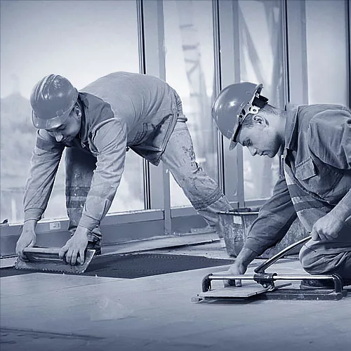 Fliesenleger arbeiten im Team auf einer Baustelle.