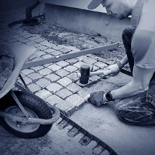 Ein Pflasterer beim Verlegen von Granitsteinen.