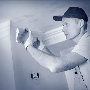 Stuckateur bei der Arbeit an einem Wandabschluss mit Zierleiste.